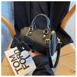 Nahaufnahme der schwarzen Zylinder-Tasche aus Litschileder mit goldenen Beschlägen