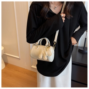 Beigefarbene zylindrische Boston-Tasche aus Leder mit Litschi-Muster und Elefantenanhänger