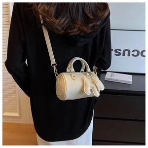Details einer cremeweißen Boston-Tasche in Zylinderform mit Narbenleder und Elefantenanhänger