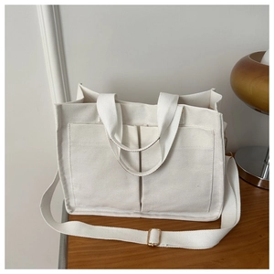 Detail of white canvas tote bag with large front pockets and adjustable shoulder strap