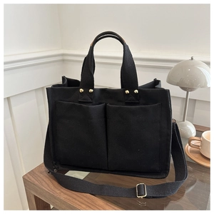 Detail of black canvas tote bag with gold rivets and adjustable shoulder strap