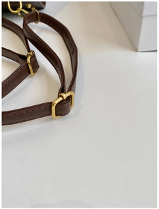 Detail of dark brown leather strap with adjustable gold metal buckle and neat stitching