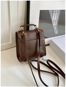 Detailed side view of vintage dark brown faux leather backpack with gold metal hardware