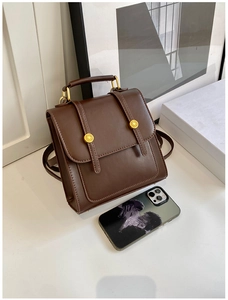 Close-up of vintage brown leather mini backpack with gold buckles and carry handle