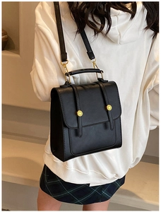 Detail of black leather multi-way backpack with golden fashion hardware on white hoodie