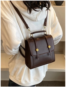 Detail of vintage dark brown PU leather backpack being worn over a white sweatshirt