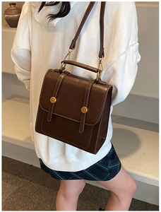 Detail of vintage dark brown PU leather backpack with gold metal buckles and top handle