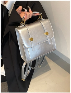 Close-up of a silver vintage backpack with gold buckle and fashion engraved text detail