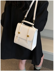 Close-up of a vintage white leather backpack with top handle and gold metal buckles