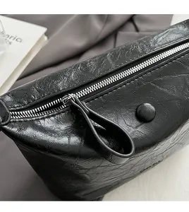 Detail of glossy pleated black PU leather texture and silver zipper on a fashion crossbody bag