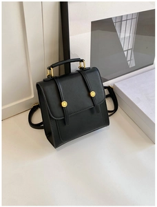Detail of black matte leather backpack with gold fashion hardware and buckle closure