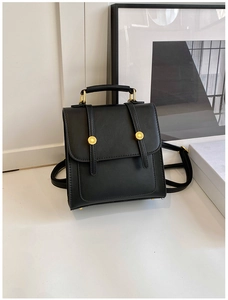 Detail of vintage black leather backpack showing gold hardware and reinforced handle grip