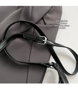 Close-up of adjustable shoulder strap with silver metal buckle on black leather bag