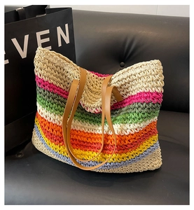 Detail of colorful woven straw tote bag with brown leather handles on leather seat