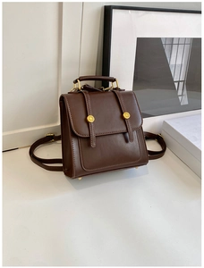 Detail of vintage dark brown PU leather backpack with gold buckles and top handle