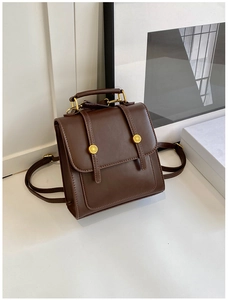 Detail of dark brown vintage faux leather backpack with gold hardware and top handle