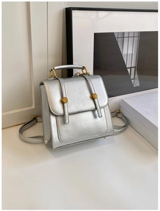 Detail of silver matte PU leather backpack featuring dual golden fashion buckle accents