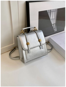 Detail of silver metallic leather backpack with golden buckles and top handle