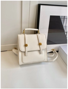 Close-up of cream white faux leather backpack with vintage metal magnetic buckles