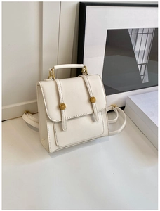 Detail of a minimalist off-white square PU leather backpack with gold metal button buckles