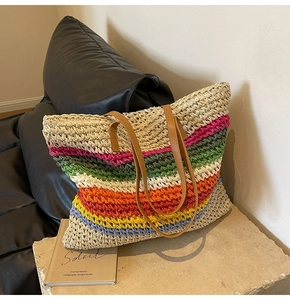 Detail of colorful striped woven tote bag with natural straw texture and brown leather straps
