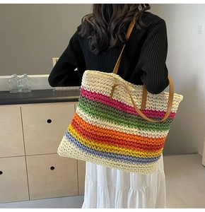 Macro detail of rainbow woven straw tote bag with multi-color stripes and leather handles