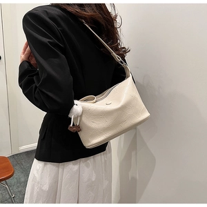 Detail of cream bucket bag with wrinkled texture, fluffy charm, and metallic zip closure