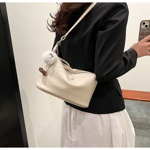 Detail of beige soft pleated leather shoulder bag with plush monster charm and embossed logo