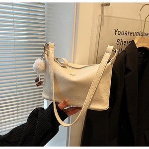 Detail of vintage pleated cream shoulder bag with magnetic snap and soft fur ball charm