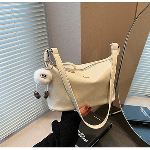 Close-up of cream bucket bag with crinkled leather texture and plush monster charm
