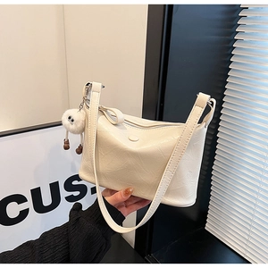 Detail of cream pleated faux leather bucket bag with cute plush keychain and zipper