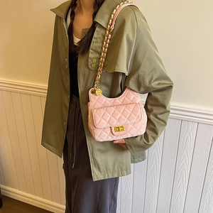 Sac bandoulière matelassé rose en daim avec chaîne dorée porté par un mannequin