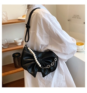 Detail of black bow shoulder bag with luxury pearl chain and textured leather material