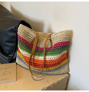 Detailed view of colorful woven straw tote bag with brown leather straps on stone step