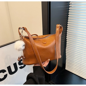 Detailed texture of brown pleated faux leather bag with stylish plush pendant accessory