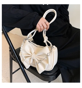 Detail of cream bow shoulder bag with pearl chain strap and textured faux leather finish