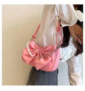 Detail of pink bow shoulder bag with pearl chain and metallic flower decorative link