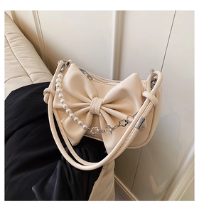 Detail of cream bow shoulder bag with decorative pearl chain and silver hardware