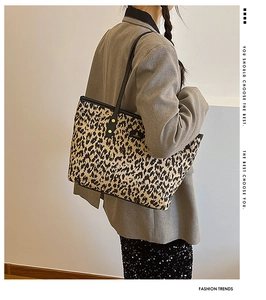 Close-up of leopard print tote bag with black trim and gold studs worn by a model