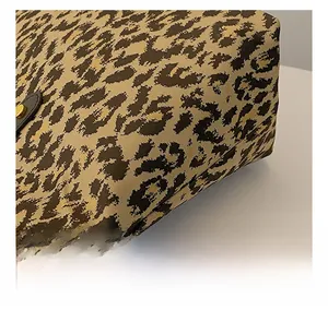 Close-up of leopard print tote bag fabric with golden hardware and textured canvas