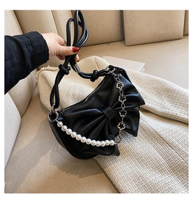 Detailed view of the black leather bow shoulder bag with pearls and clover chain