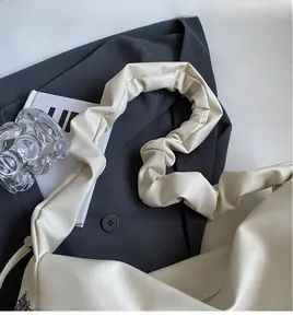 Détail de la bandoulière plissée crème douce sur un grand sac cabas au design minimaliste
