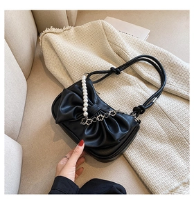 Detail of black bow shoulder bag with elegant pearl chain and floral metal charms