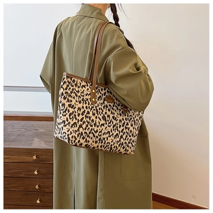 Side view of leopard print tote bag styled with a dark green coat on a female model