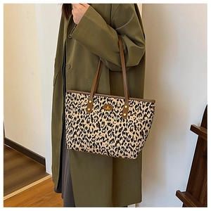 Detailed side view of leopard print tote bag with brown leather handles and gold studs
