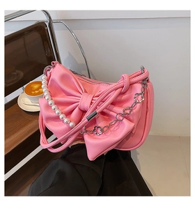 Close-up of pink bow shoulder bag with pearl handle and floral metal chain details