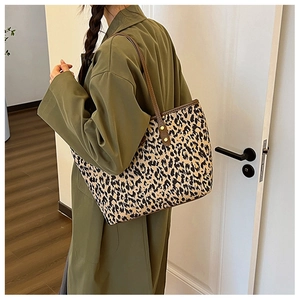 Detailed side view of leopard print tote bag with brown leather straps on model