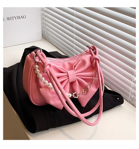 Detail of pink bow handbag featuring pearl and metal flower decorative chains