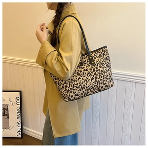 Close-up of leopard print tote bag with black shoulder strap and gold metal buckle