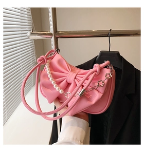 Detailed macro of pink patent leather bag with oversized bow and pearl chain strap